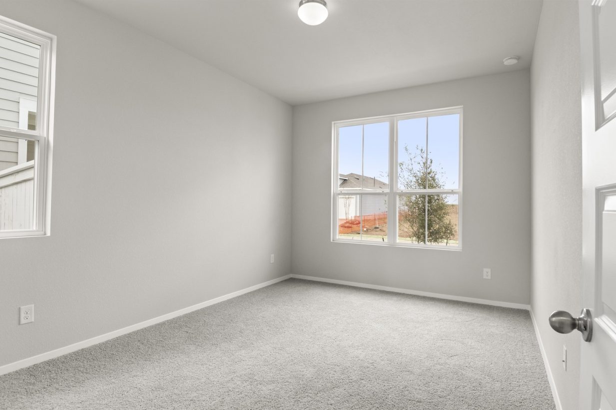 Image of bedroom with light grey walls and carpet with a window