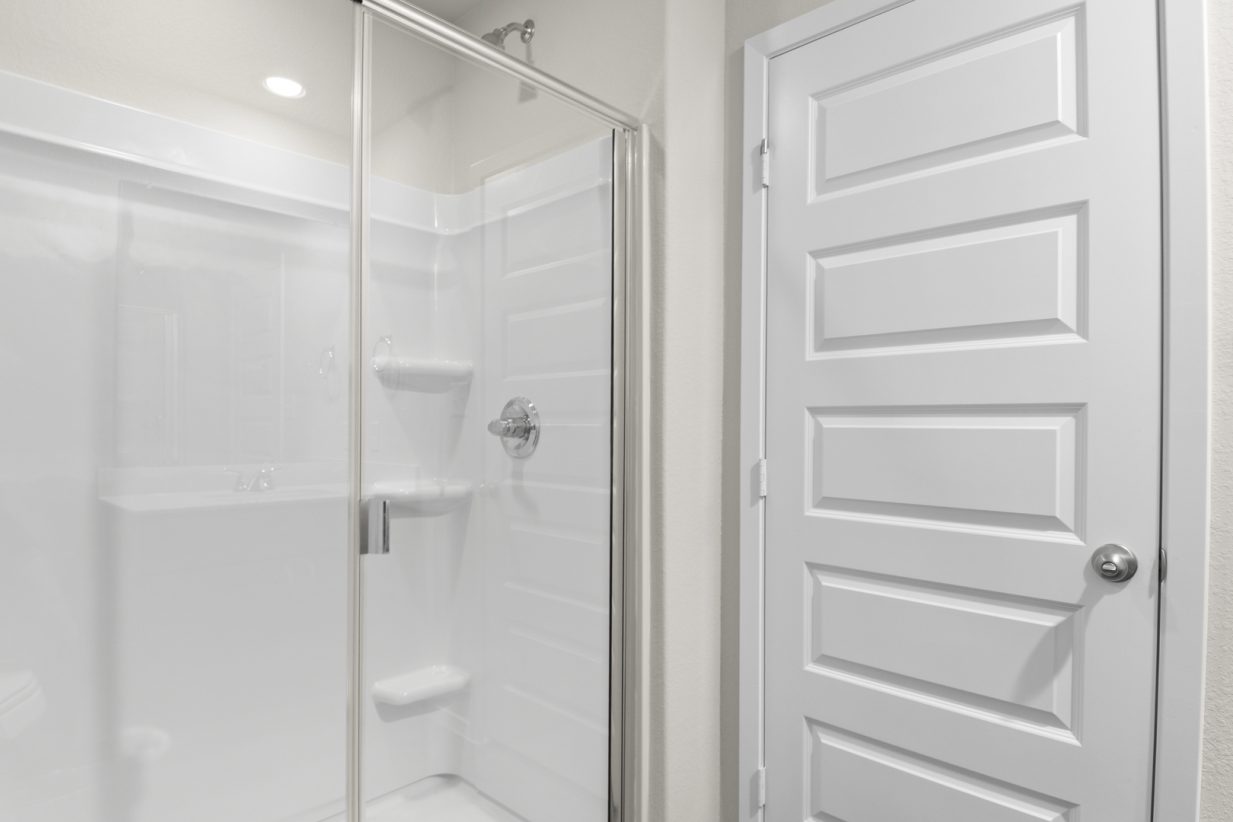 Image of a primary bathroom with a white vinyl walk-in shower