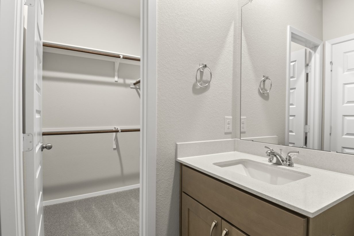 Image of primary bathroom with a sink and mirror next to a primary closet