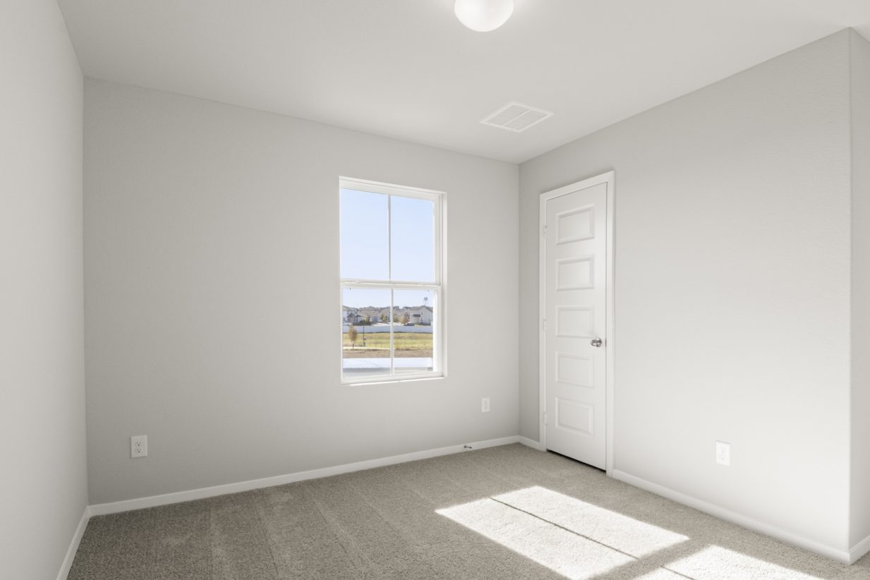 Image of a bedroom with light grey walls, brown carpeting and a window