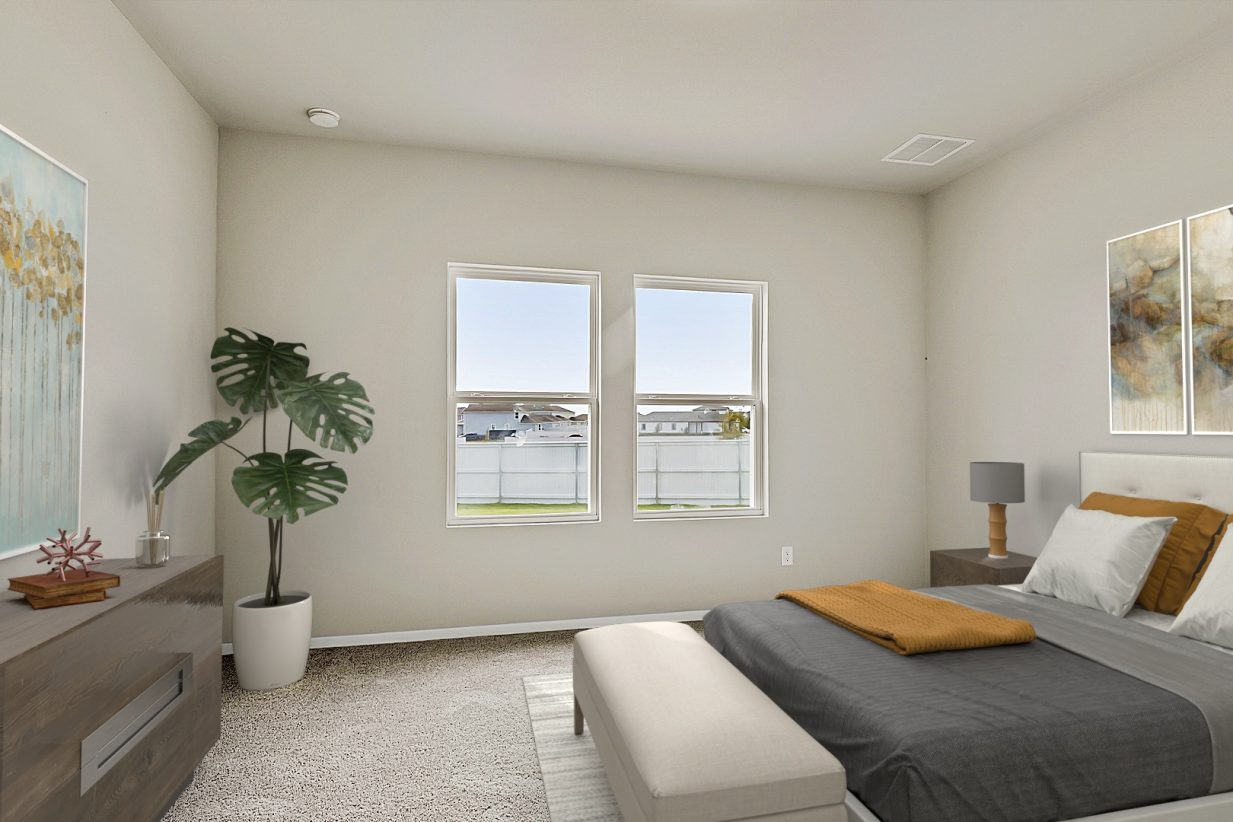 Image of a primary bedroom with a queen bed and bed frame, a large plant in the left corner and a side table with a lamp in the corner