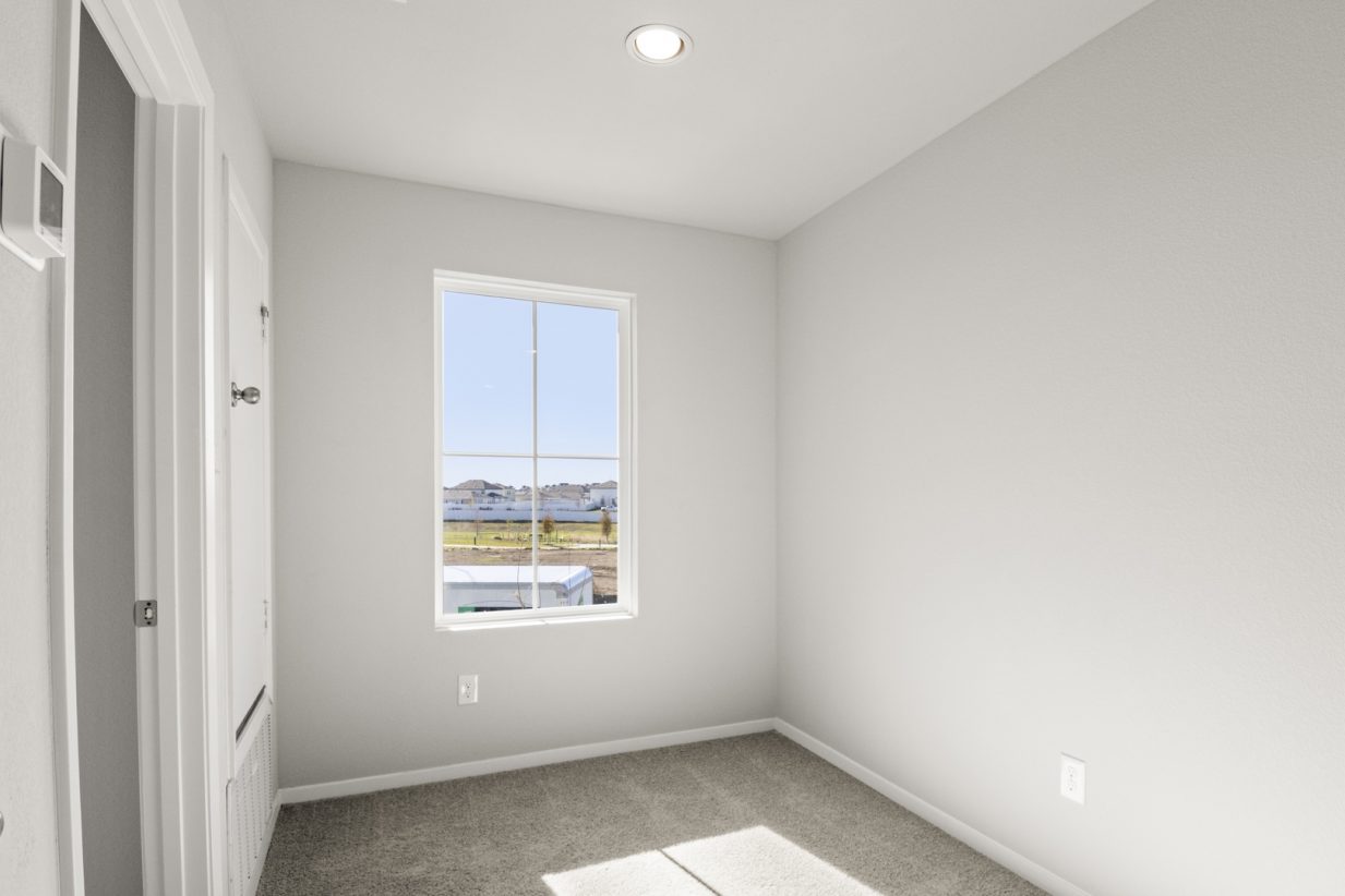 Image of a landing room with light grey walls, tan carpeting and a window
