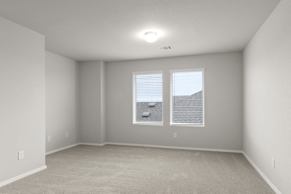 Image of a flex space area with tan carpeting and light grey walls with two large windows