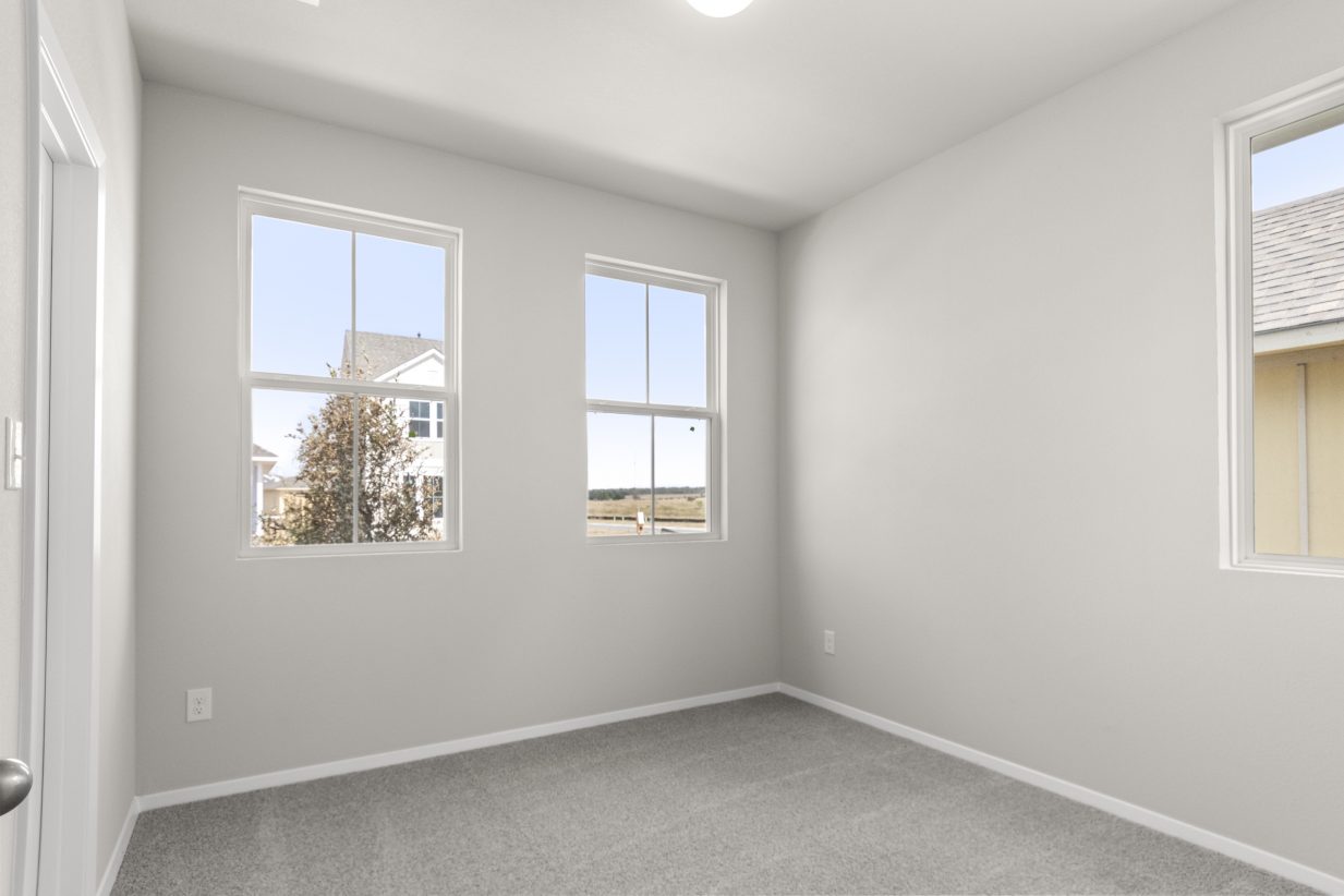 Image of a bedroom with light grey carpeting and walls and windows