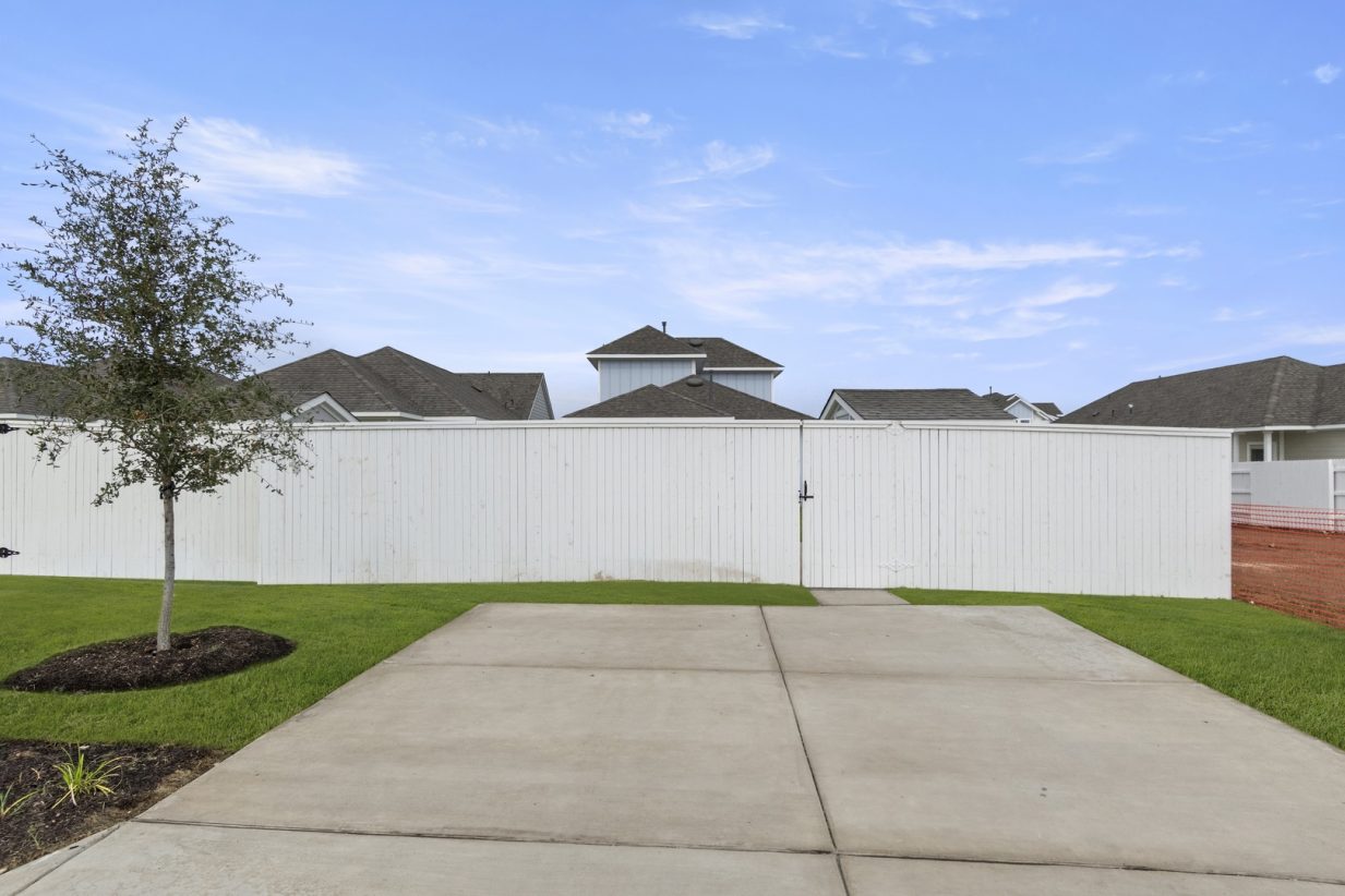 Image of back cement driveway with a white fence