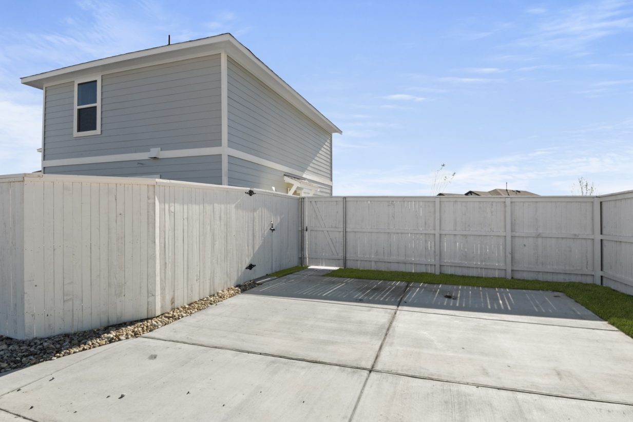 Image of a cottage home driveway with a white wooden fence