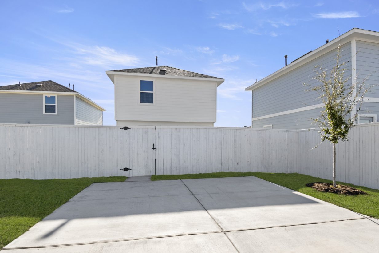 Image of a cottage home driveway with a white fence and a blue sky in the background