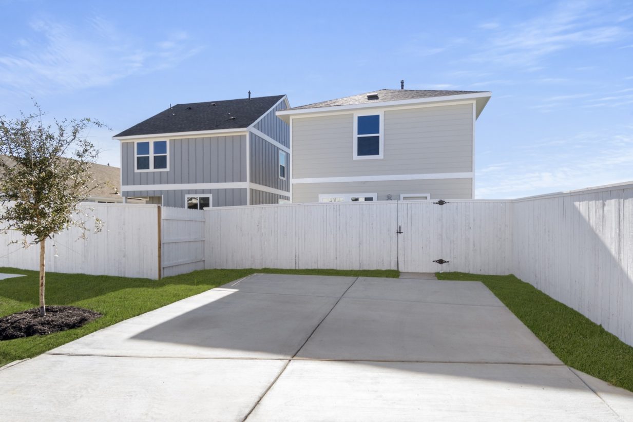 Image of a cottage home driveway with a white wooden fence