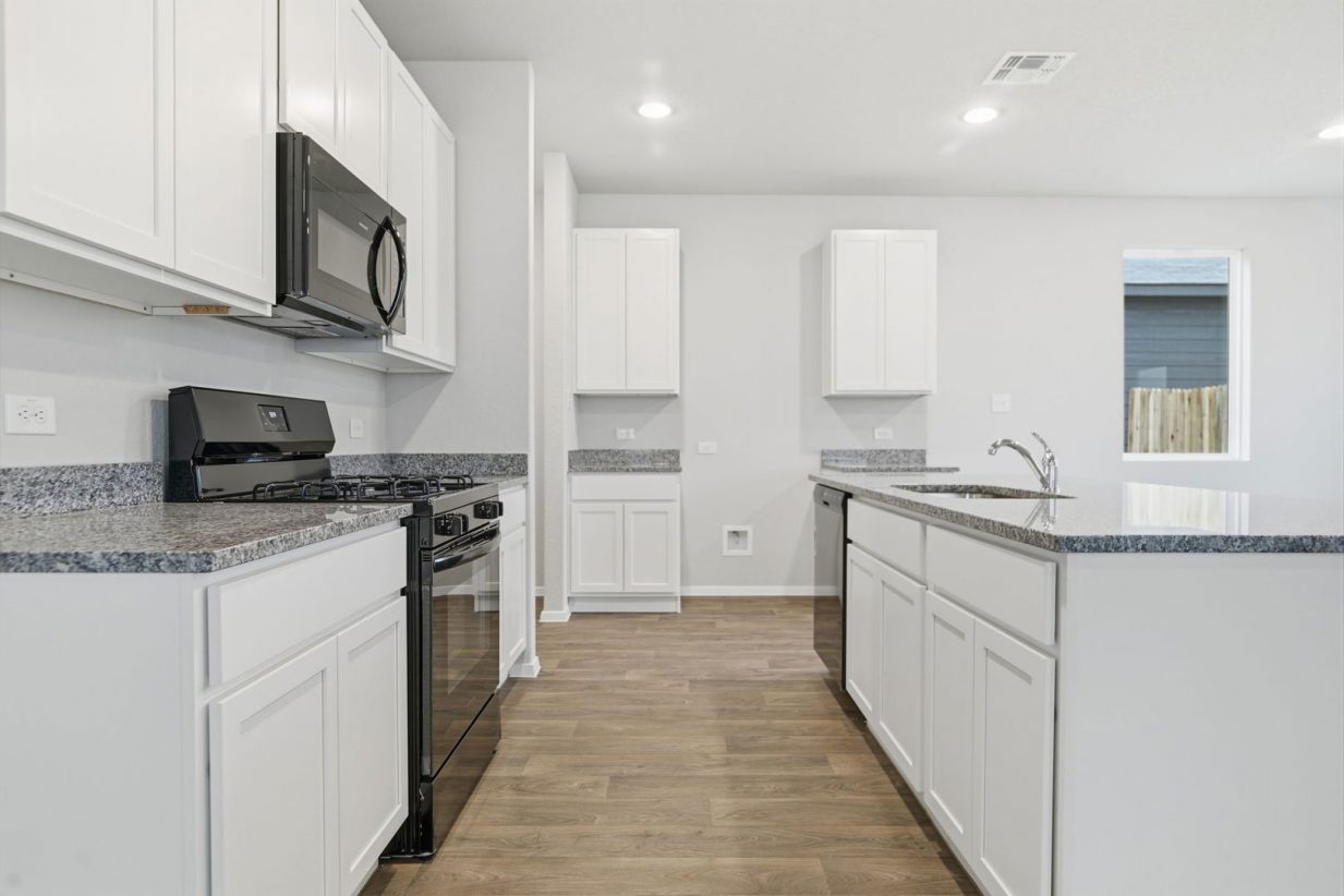 Image of a kitchen with white cabinets, granite countertops, black appliances and a center island
