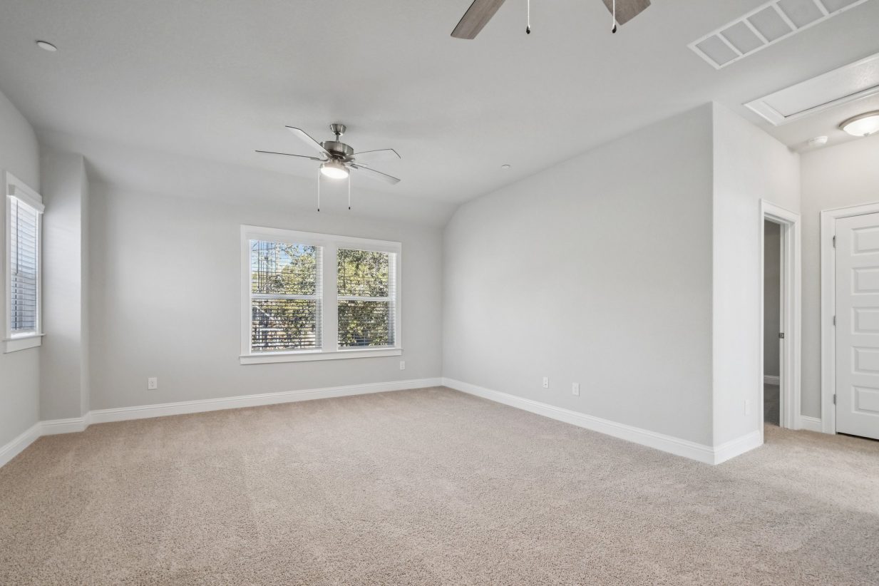 Image of a bedroom with light grey walls, tan carpeting, windows and white trim