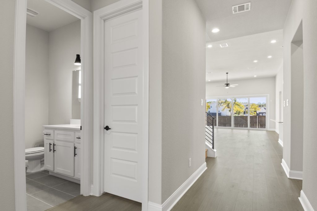 Image of a two story home foyer with dark wood flooring and light grey painted walls with a white door and trim