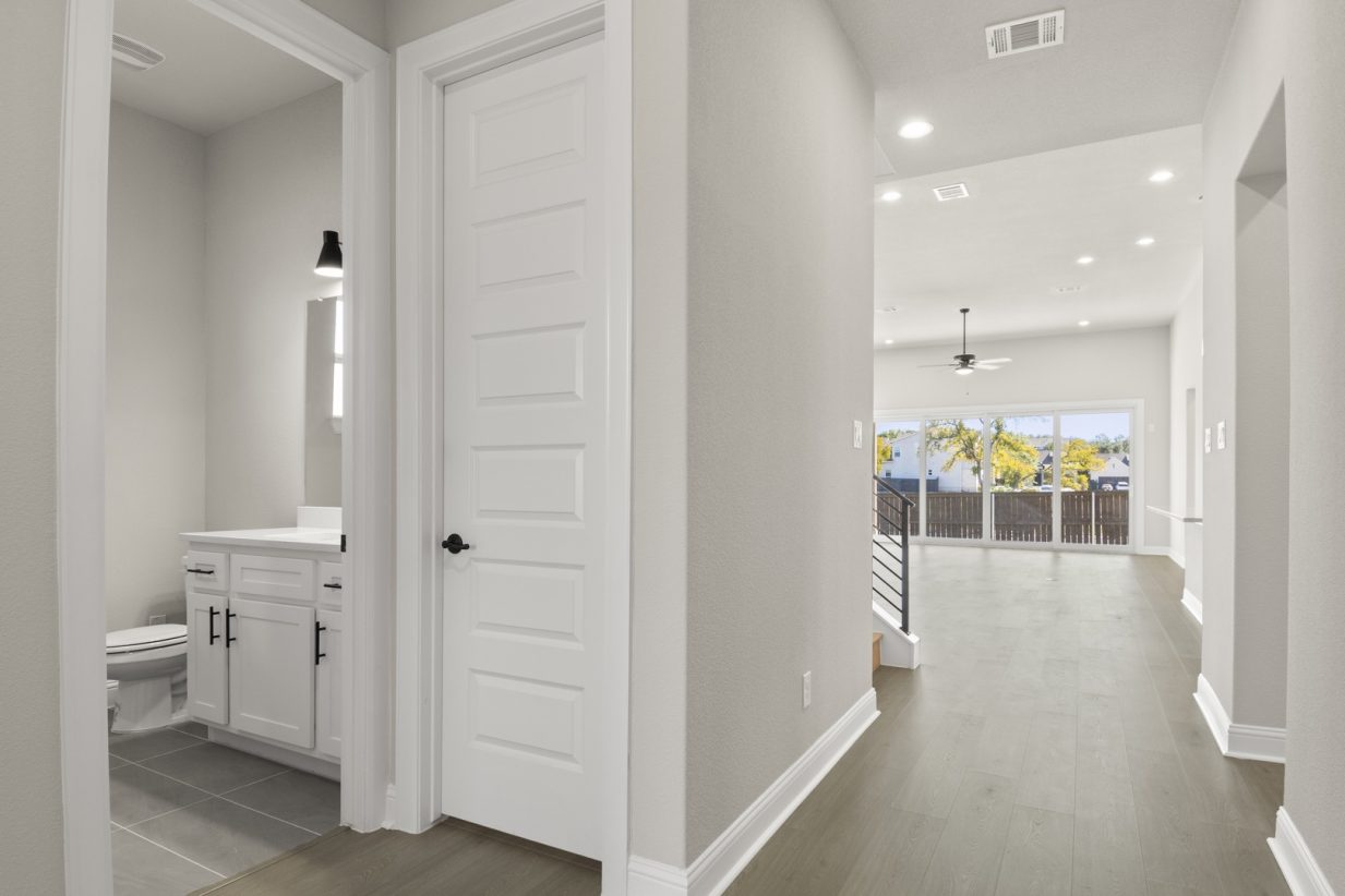 Image of a two story home foyer with dark wood flooring and light grey painted walls with a white door and trim