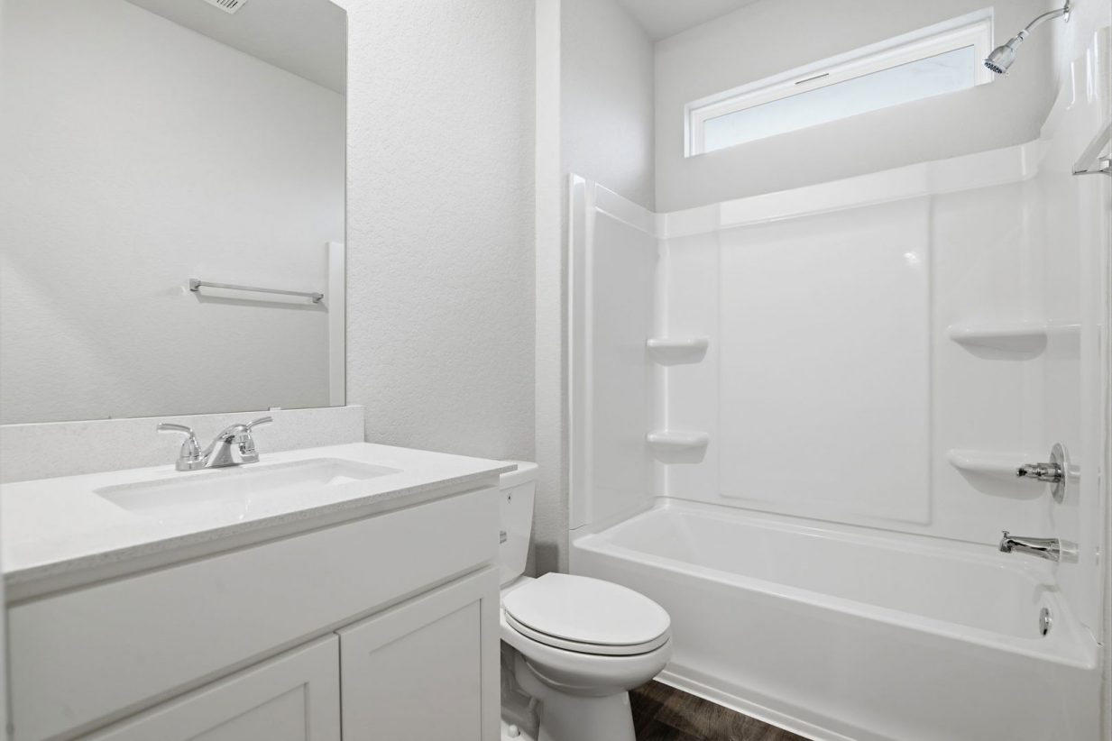 Image of a bathroom with white cabinets, a white vanity, a mirror and a white shower and tub