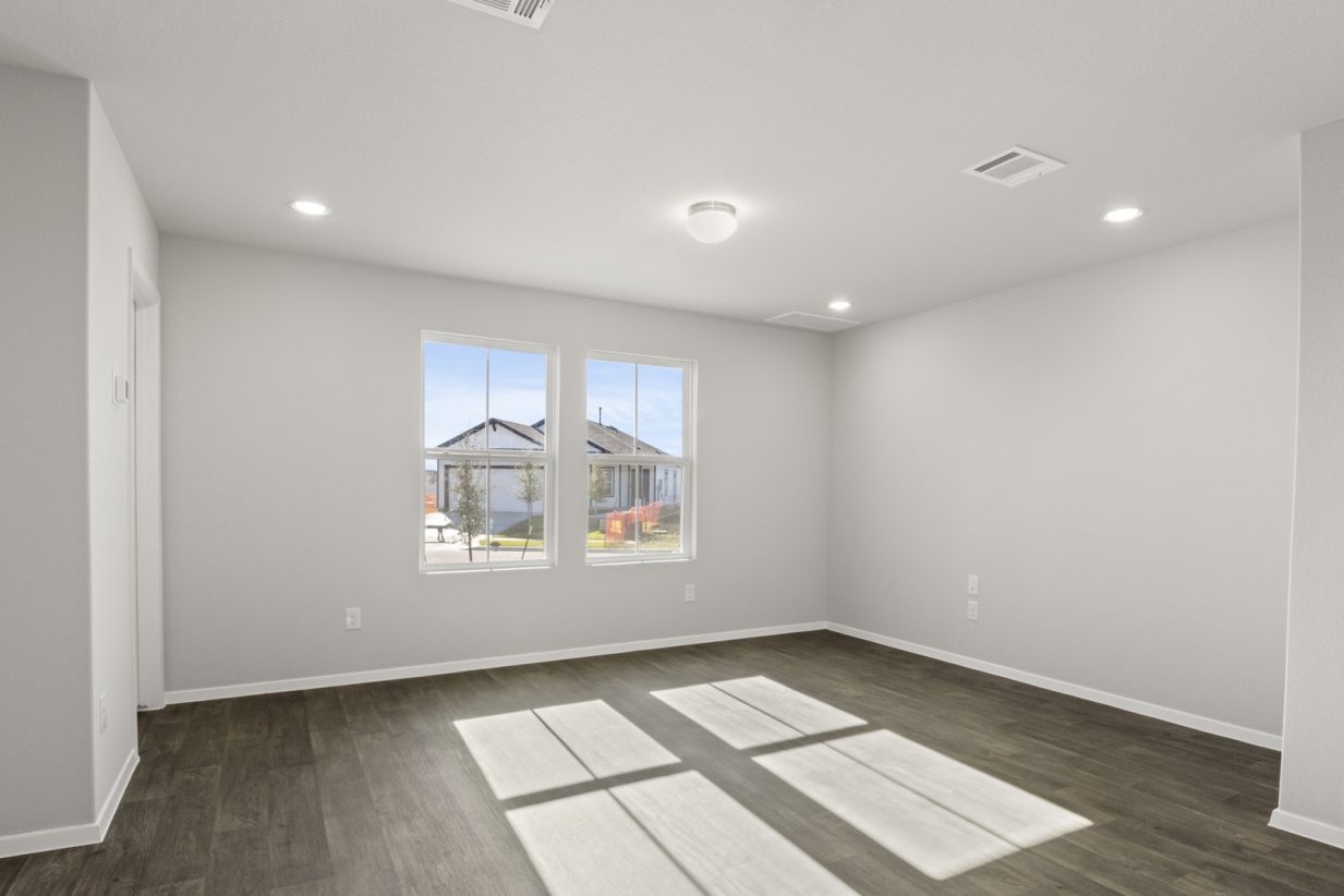 Image of a cottage home living room with dark vinyl flooring with light grey walls and two large windows