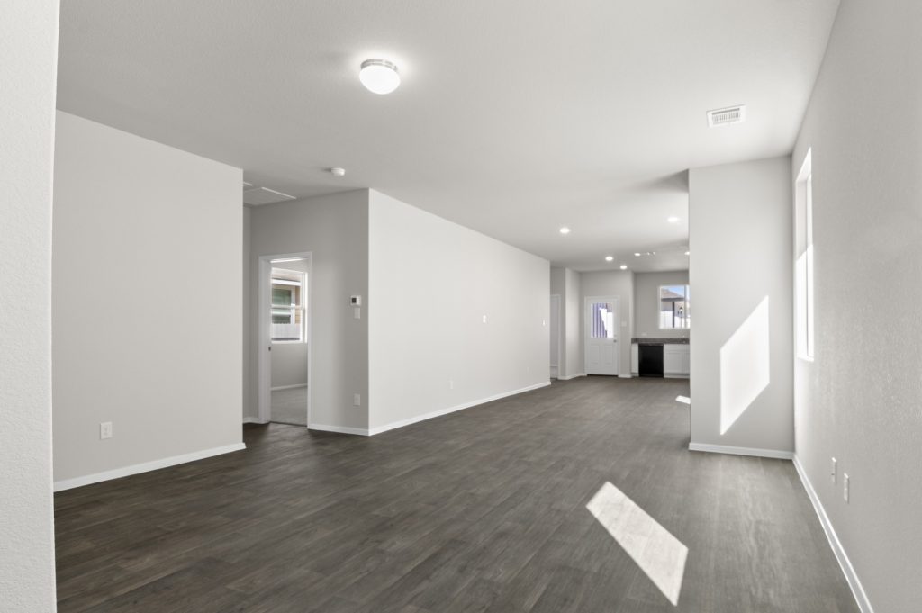 Image of a living room with light grey walls, dark brown flooring and white trim