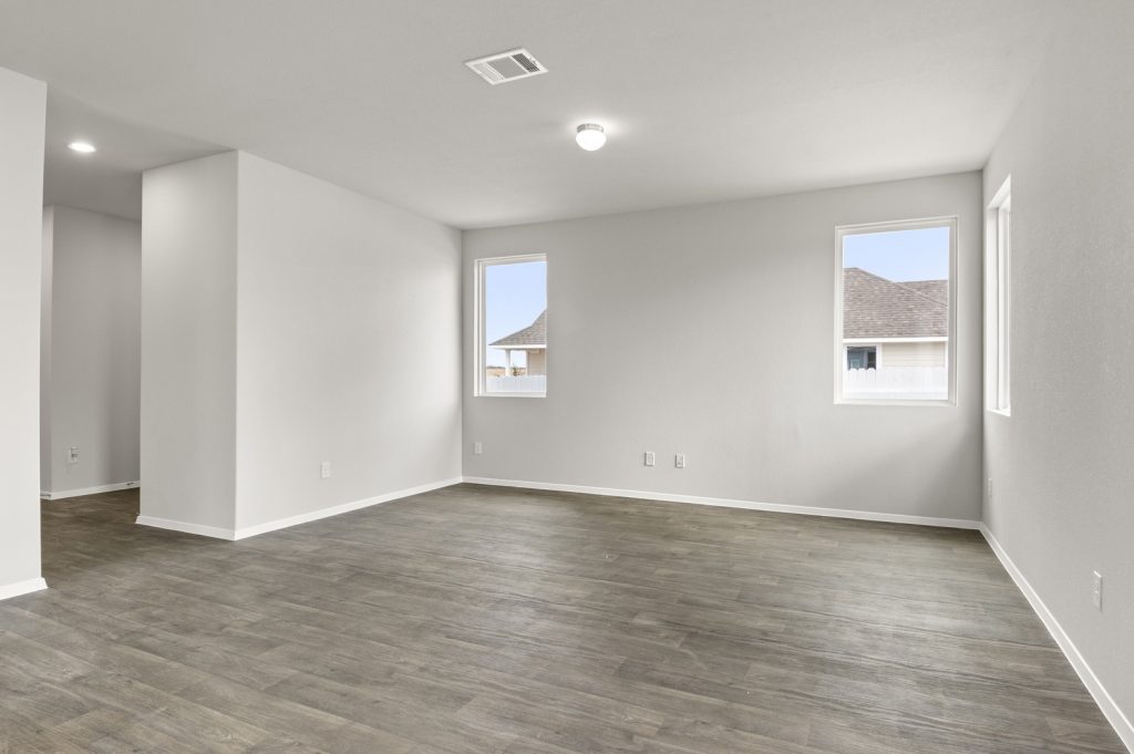 Image of two story home living room with brown flooring and light grey walls and windows