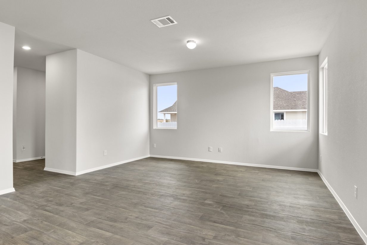 Image of two story home living room with brown flooring and light grey walls and windows