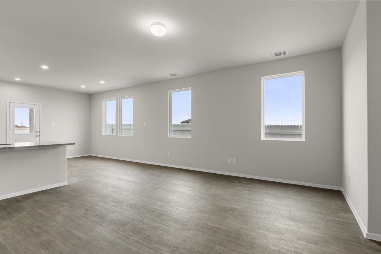 Image of a living room with cream walls, dark brown vinyl flooring, windows and white trim