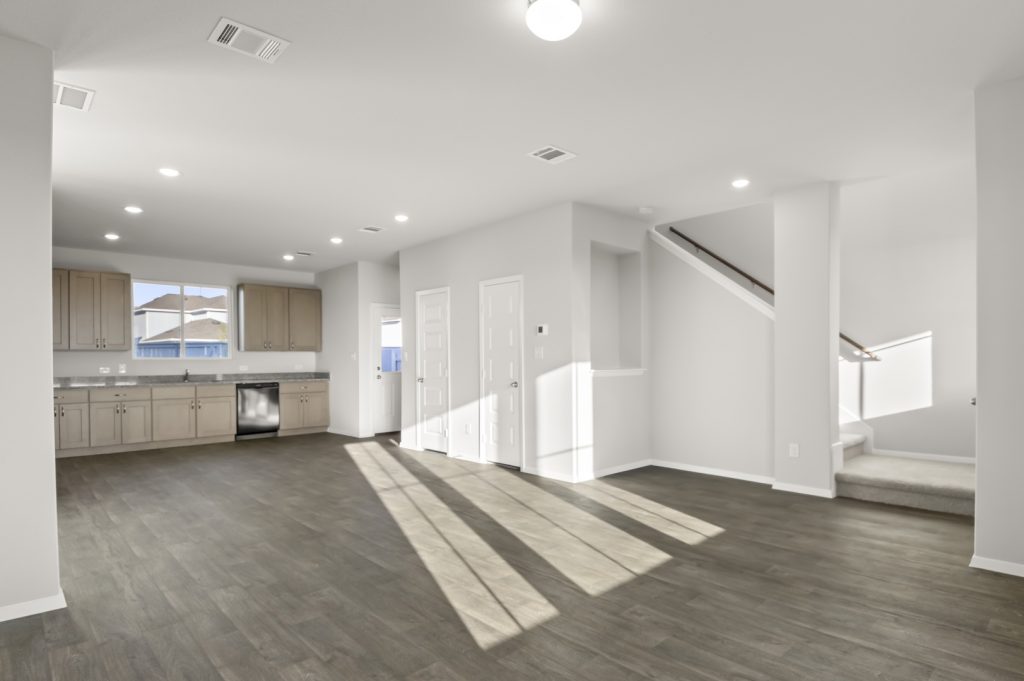 Image of a living room with a staircase leading upstairs and a open layout kitchen