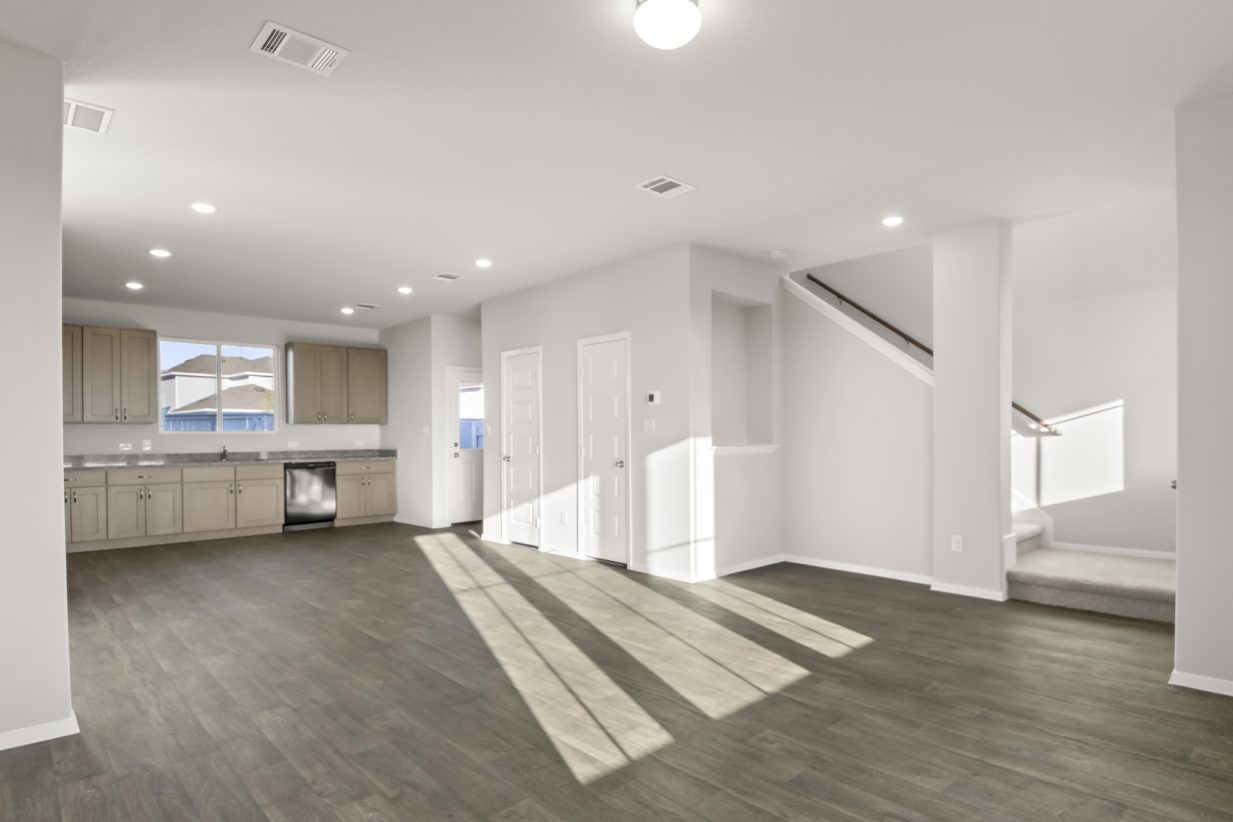Image of a living room with a staircase leading upstairs and a open layout kitchen