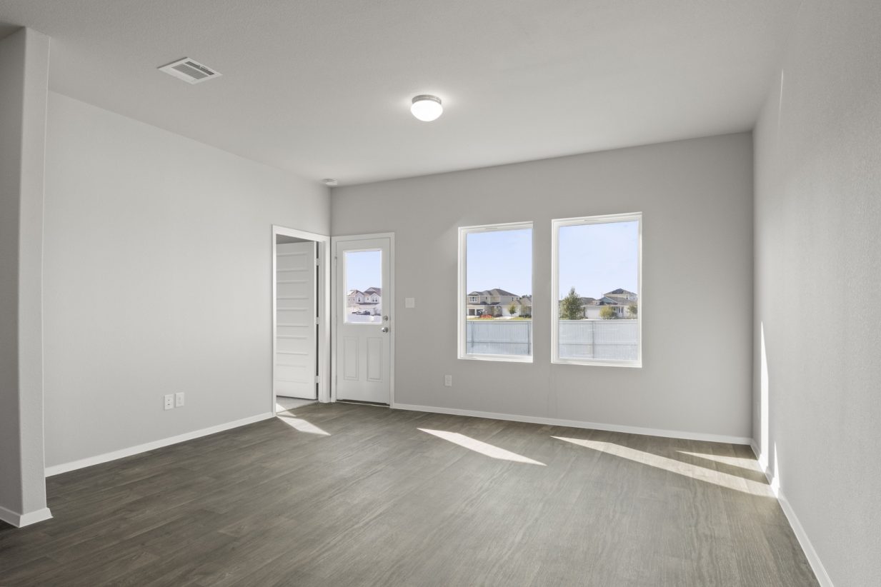 Image of a living room with brown flooring and light grey walls with two windows