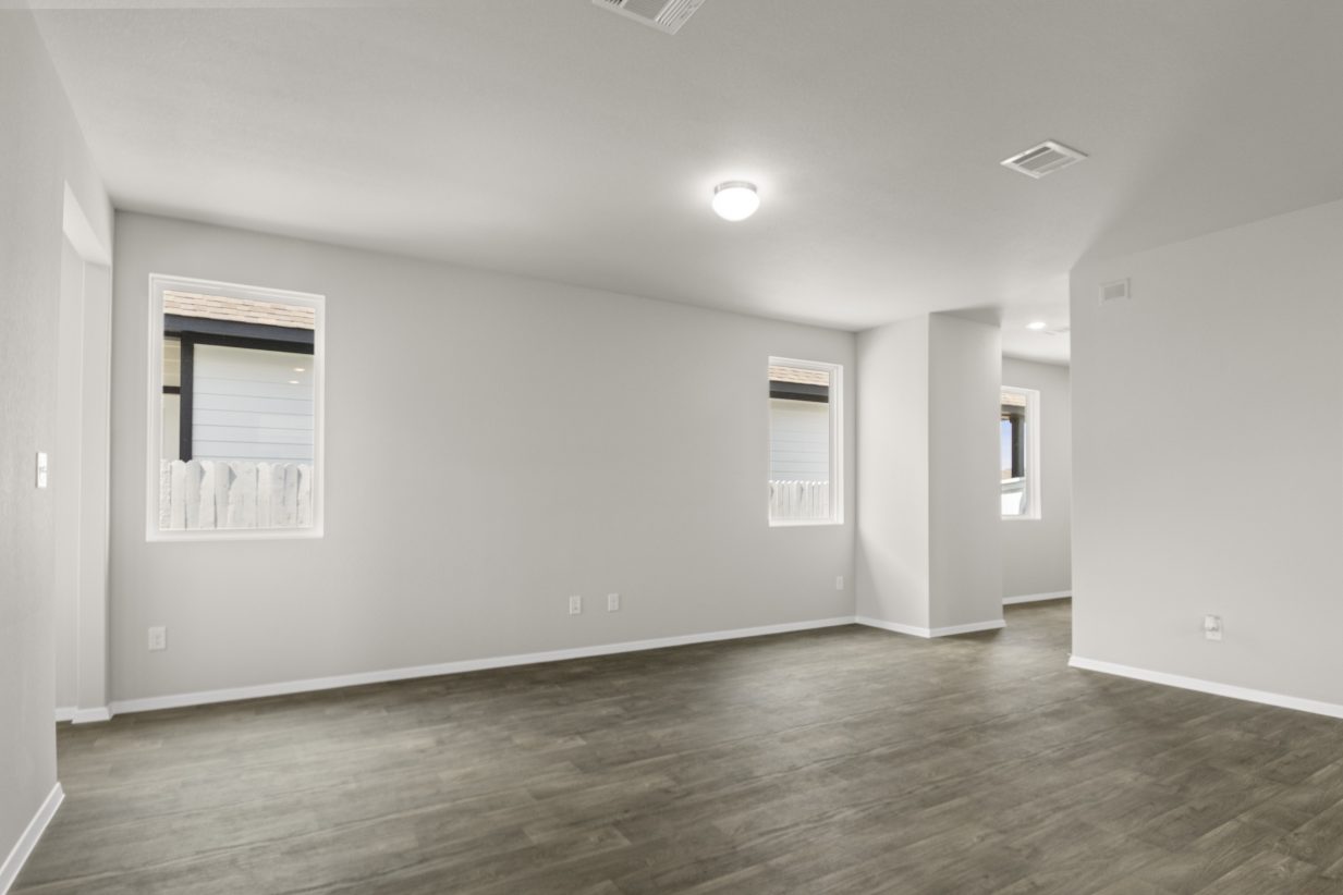Image of a living room with dark vinyl flooring, light grey walls and windows