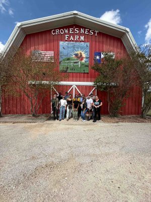Image of Crowe's Nest Farm red barn with people in front of it and a blue sky with clouds in the background.