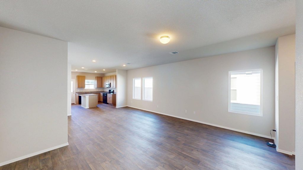 Image of a one story home with brown wood-like flooring and light grey painted walls with two windows
