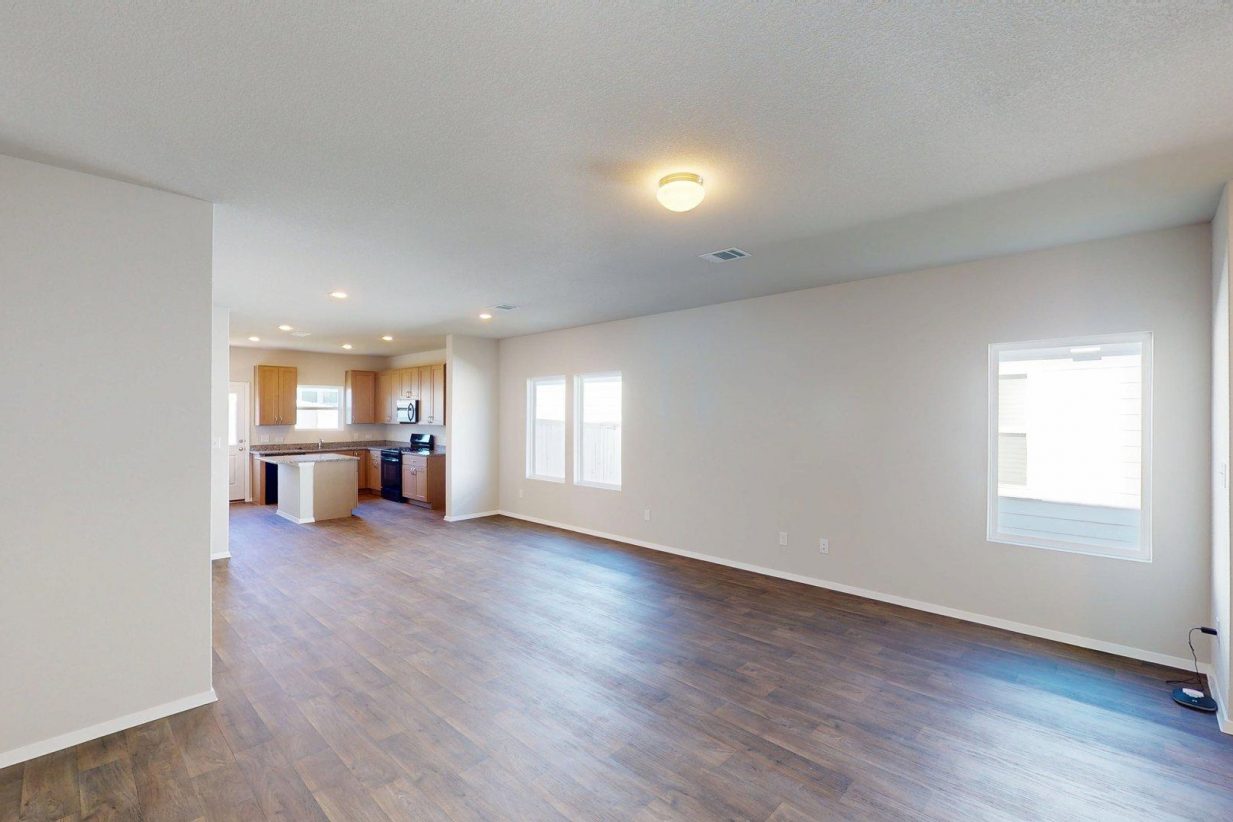 Image of a one story home with brown wood-like flooring and light grey painted walls with two windows