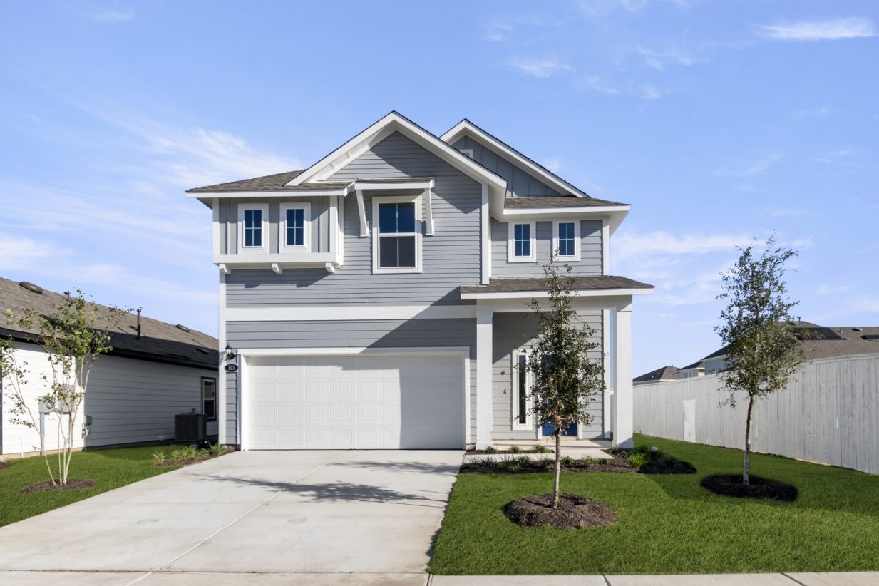 Image of the exterior of a blue two story home with a dark blue door and a cement driveway with a white two car garage