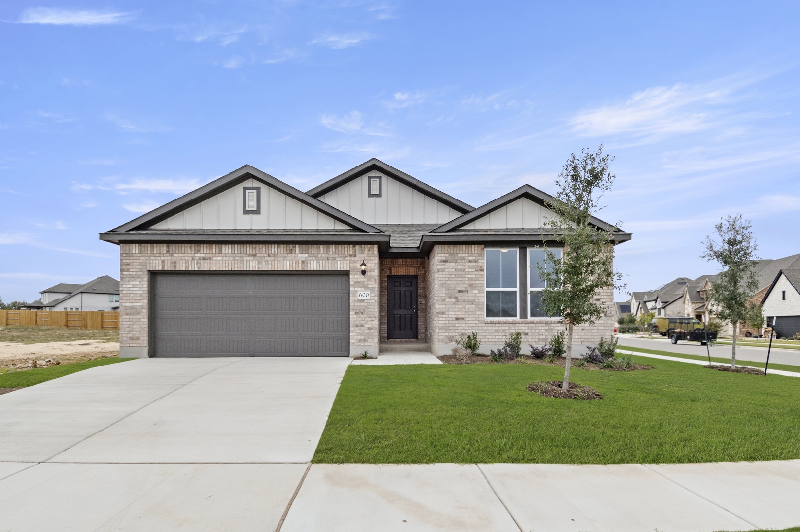 Image of a one story brick home exterior with a blue door, brown garage and a cement driveway
