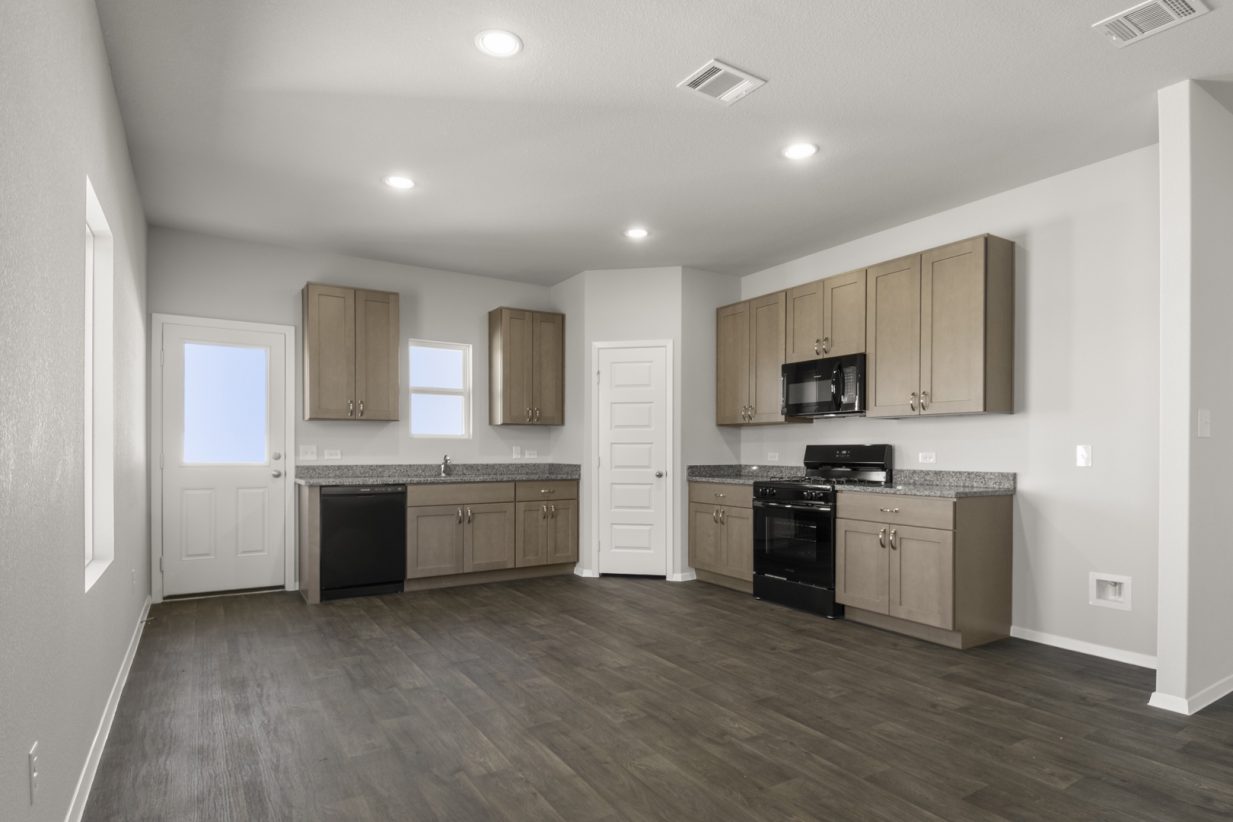 Image of a dining/ kitchen with dark vinyl flooring, light brown cabinets, black appliances and a window above the window