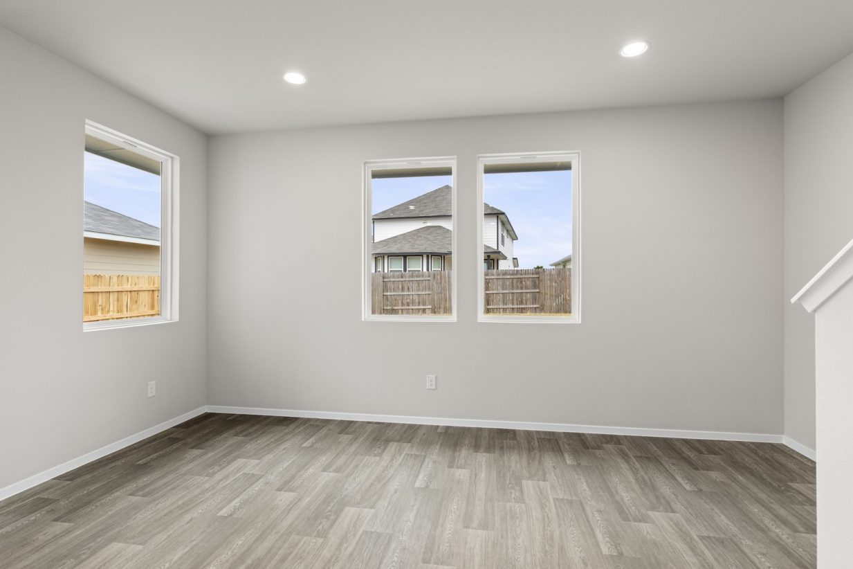 Image if a dining room with cream walls, light brown flooring, windows and white trim