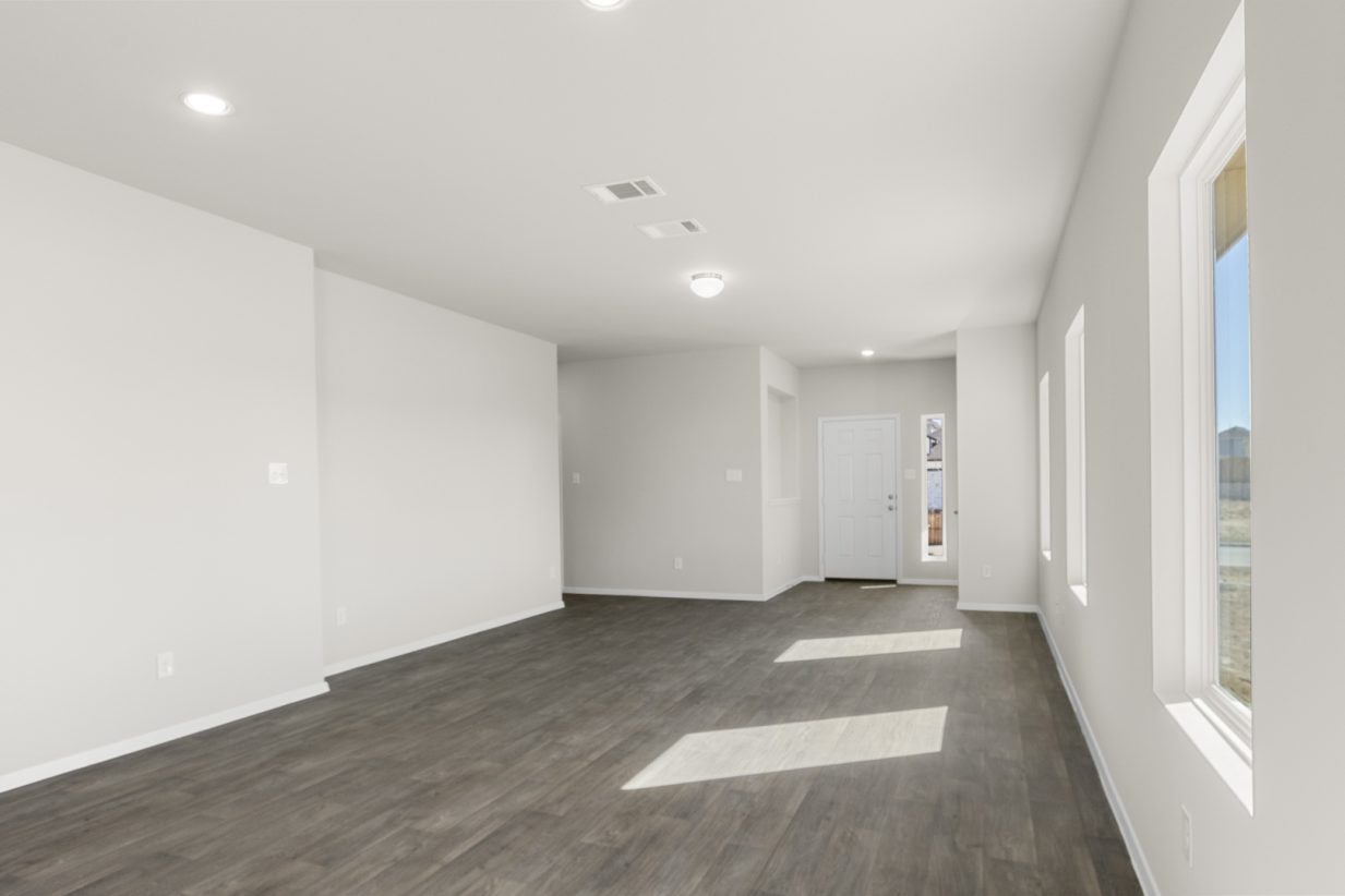 Image of a dining room area with cream walls, dark brown flooring, a white front door and white trim