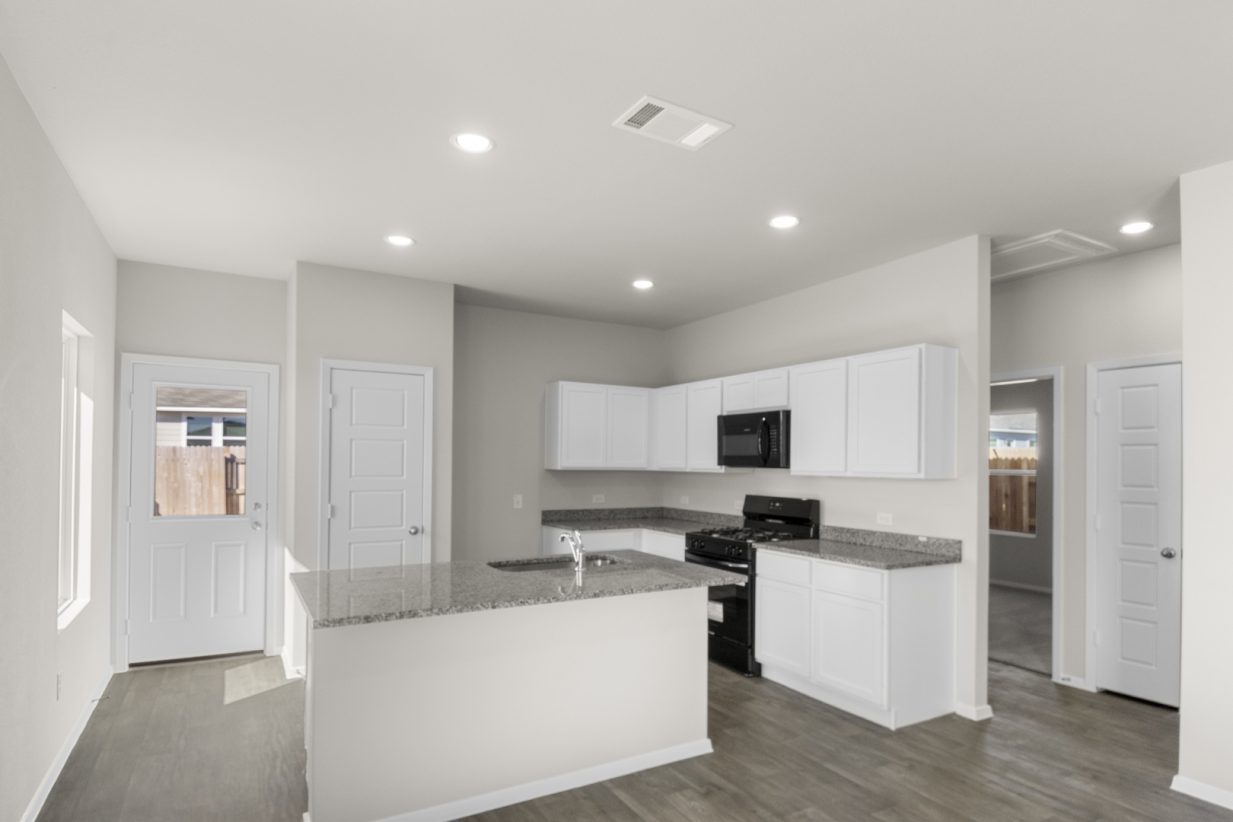 Image of a kitchen with cream walls, white cabinets, granite countertops, a center island, black appliances and a back door