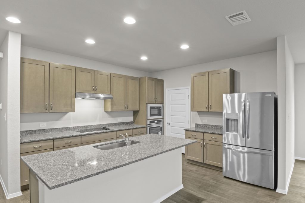 Image of a kitchen with light brown cabinets, granite countertops with stainless steel appliances