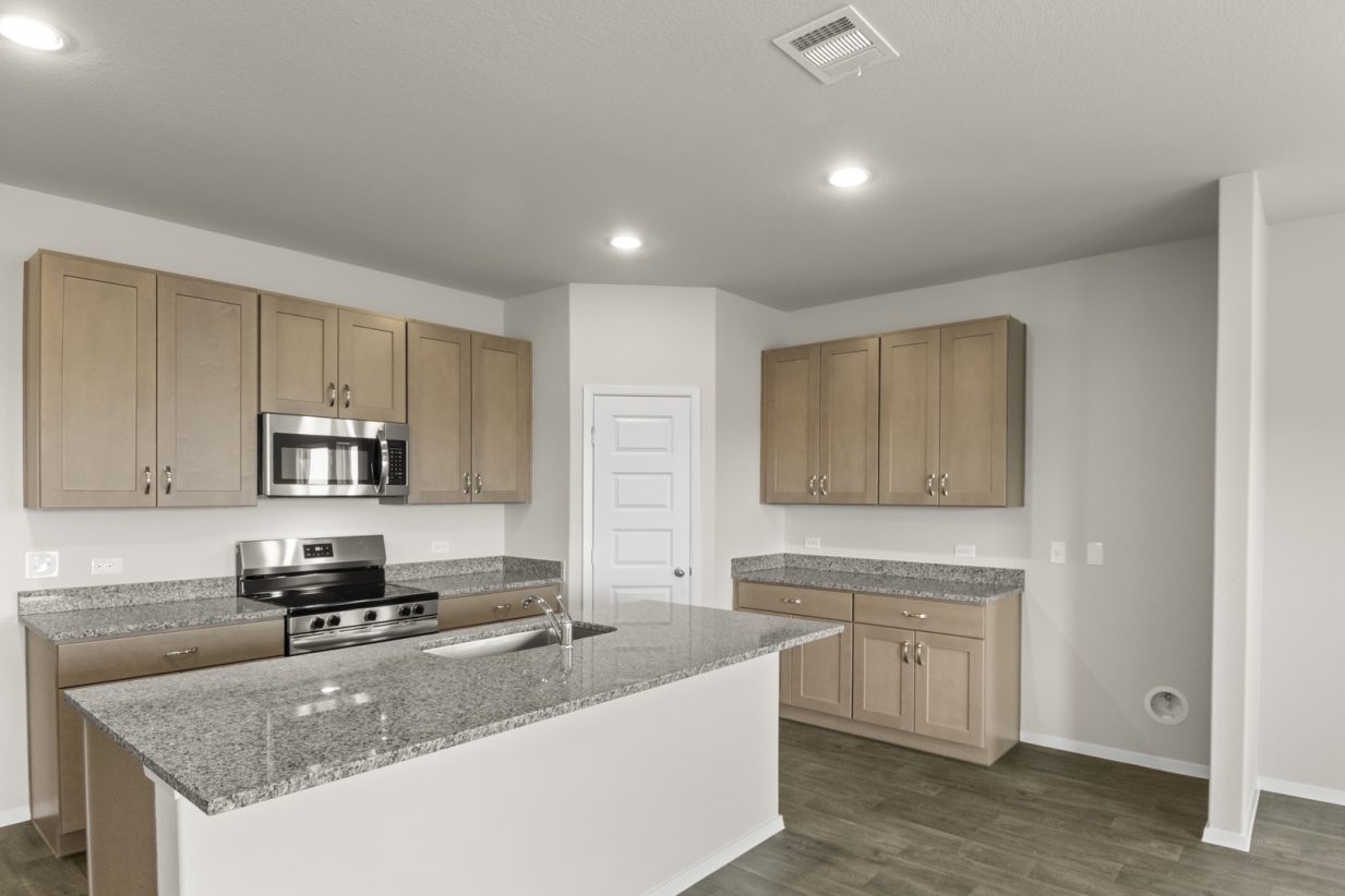 Image of a kitchen with a center island, light brown cabinets, granite countertops, and black and stainless steel appliances