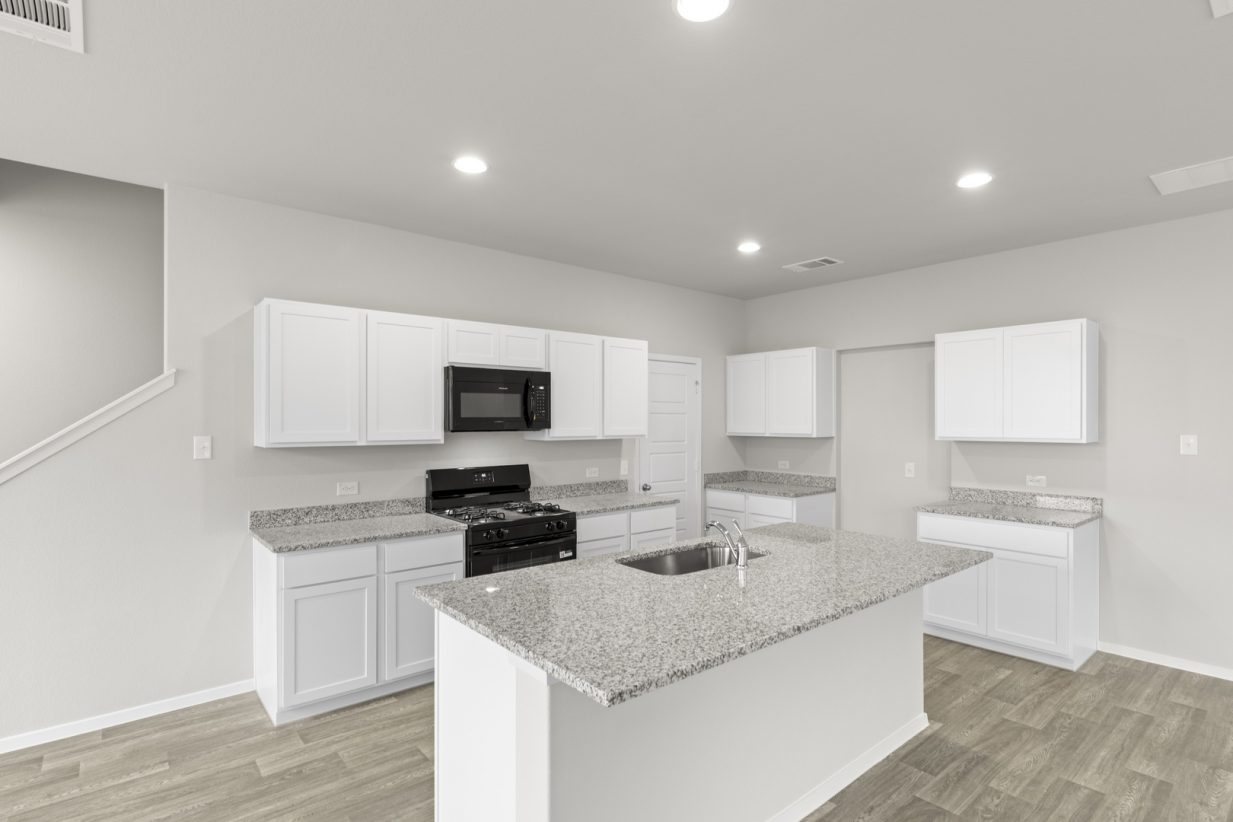 Image if a kitchen with white cabinets, granite countertops, black appliances, and a center island