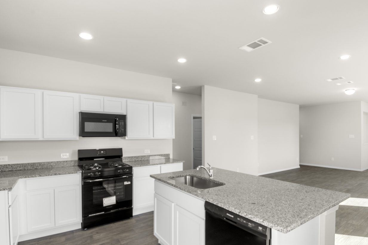Image of a kitchen with white cabinets, granite countertops, black appliances and a center island