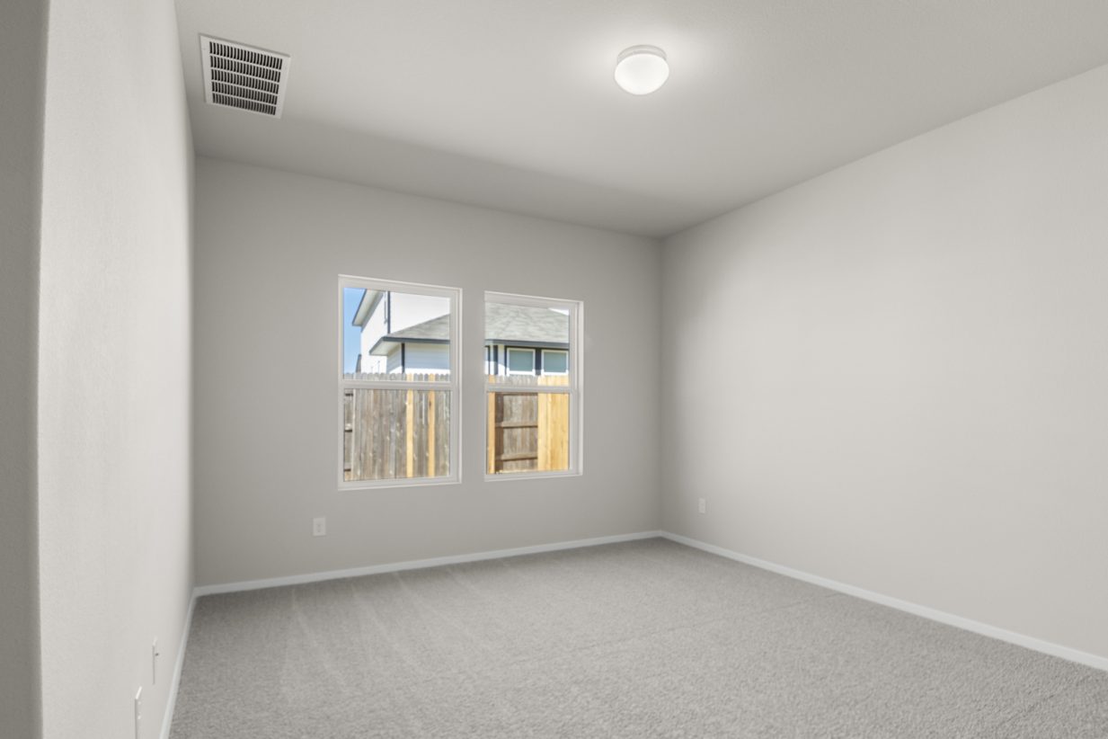 Image of a primary bedroom with cream walls, tan carpeting. two windows and white trim