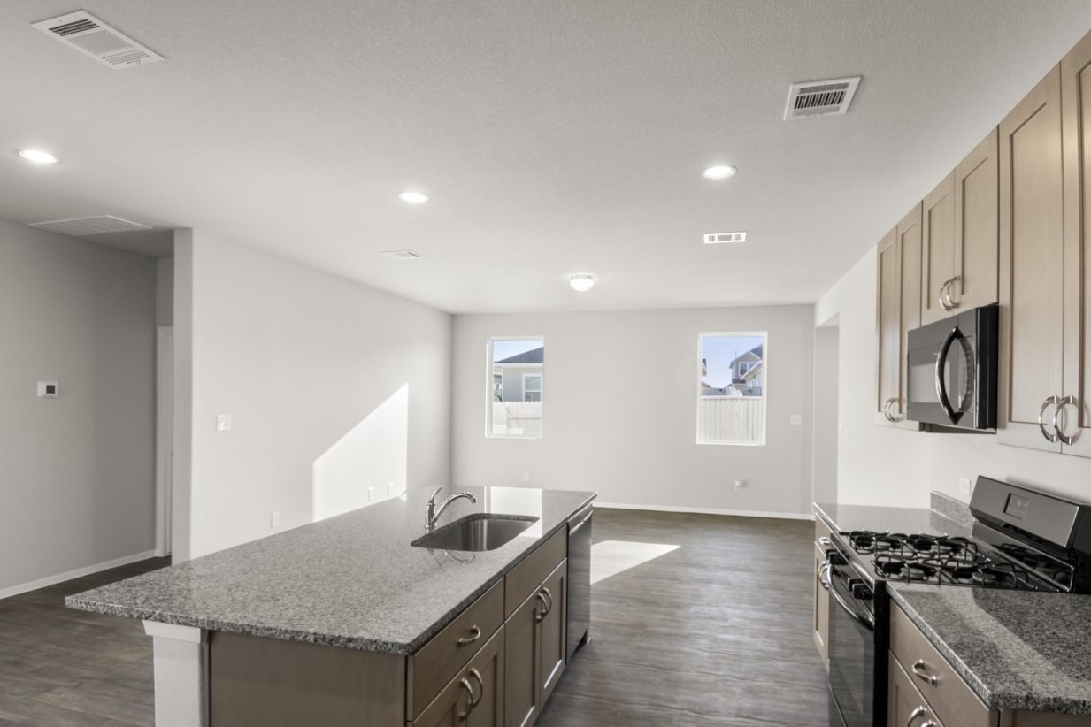 Image of a kitchen with brown cabinets and granite countertops and black appliances