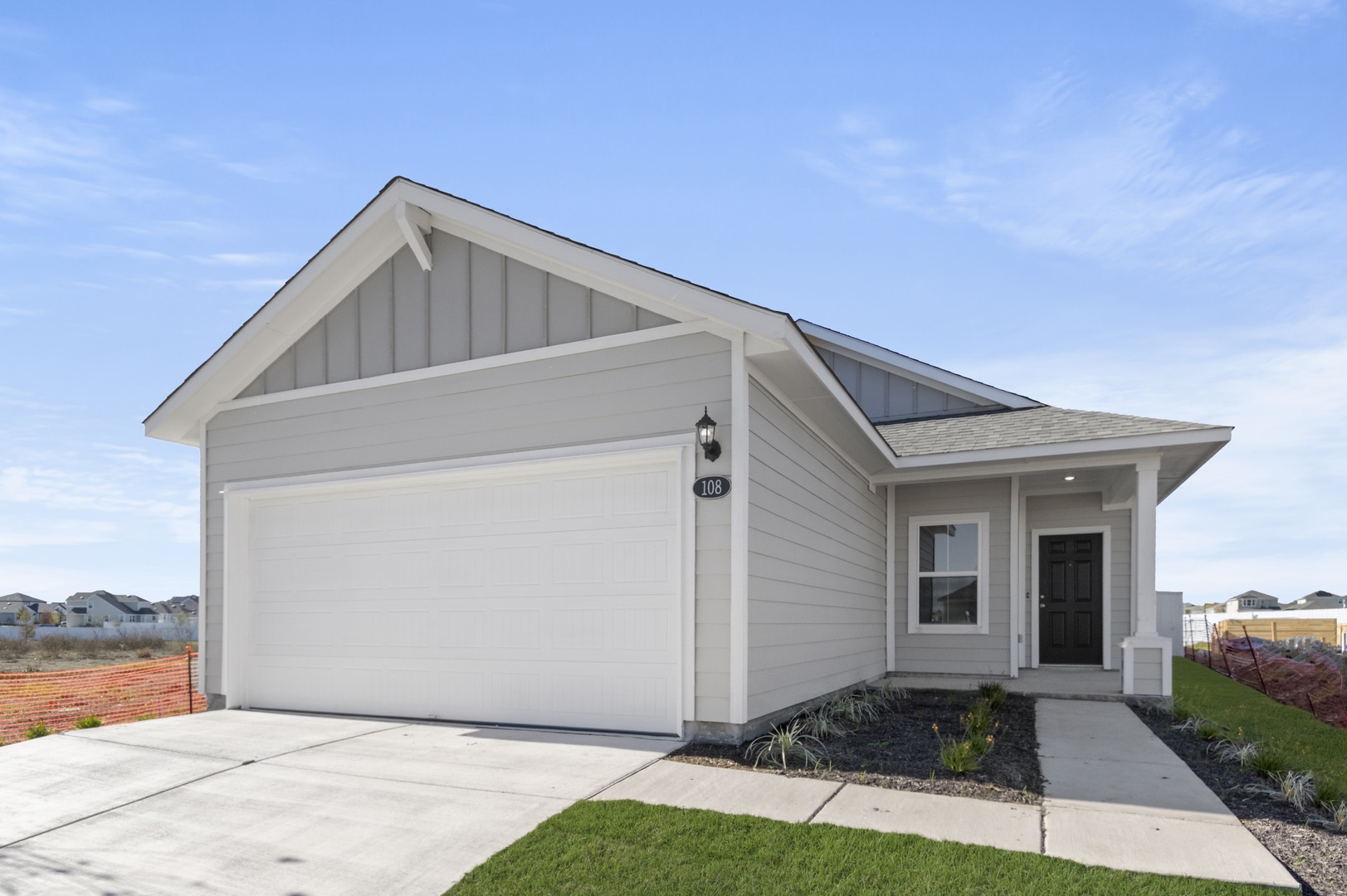 Image of a front exterior light grey one story home with a white door garage, a cement driveway and a charcoal front door