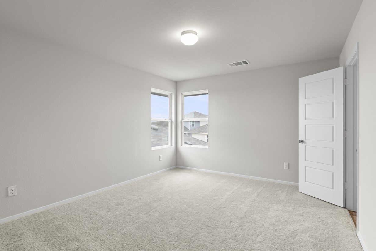 Image of a bedroom with cream walls, tan carpeting, two windows in the corner and white trim