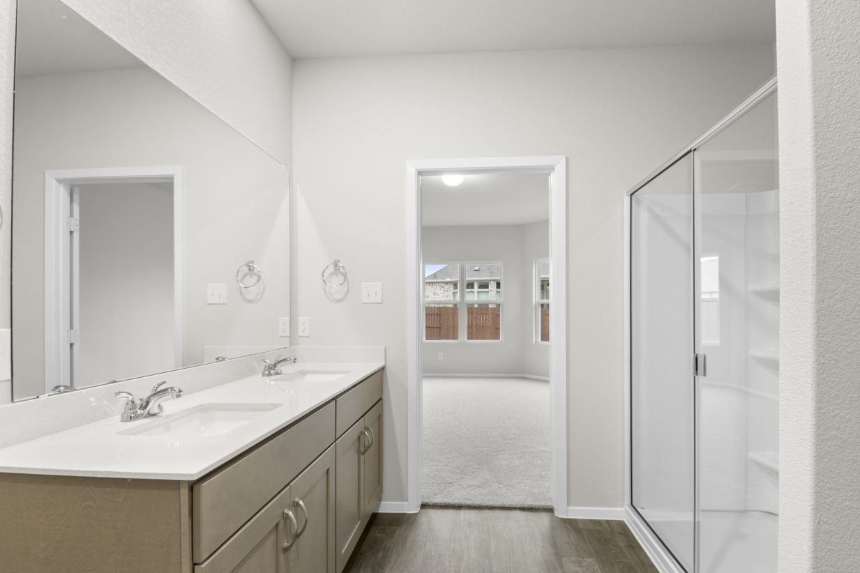 Image of a primary bathroom with a double white vanity with a large window and a white vinyl walk-in shower