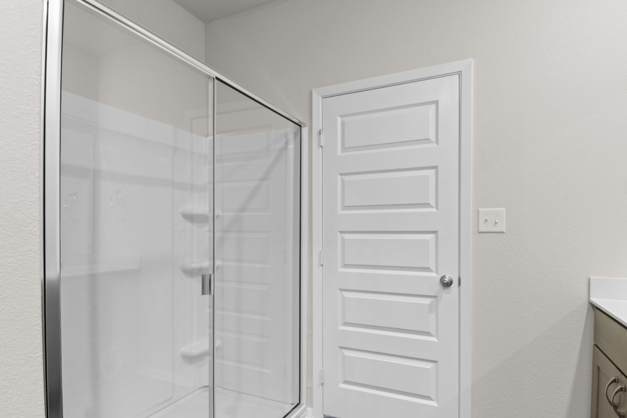 Image of a primary bathroom with a vinyl walk-in shower