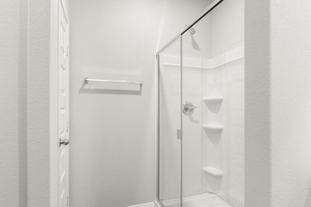 Image of a primary bathroom standing shower with white vinyl
