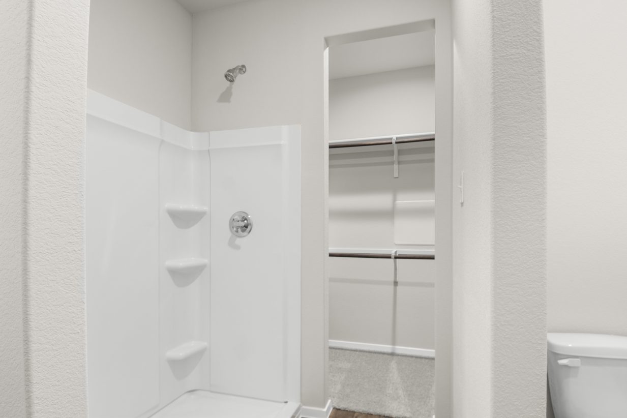 Image of a primary bathroom with a white walk-in shower and a walk-in closet