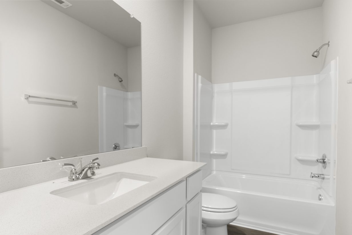 Image of a bathroom with white cabinets and vanity, a large mirror and a white shower and tub