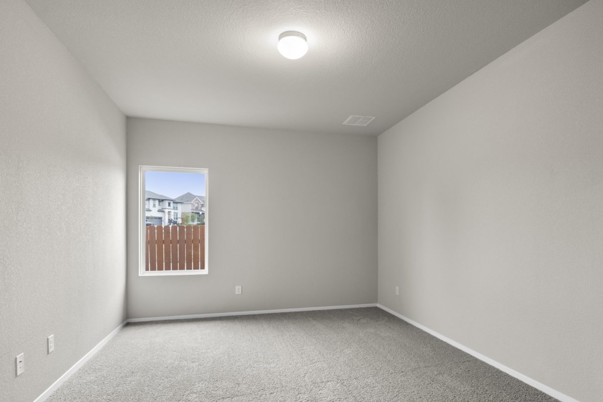 Image of a flex space with tan carpeting and light grey walls with a window