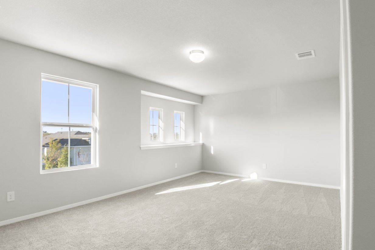 Image of a bedroom with tan carpeting and light grey painted walls with two windows